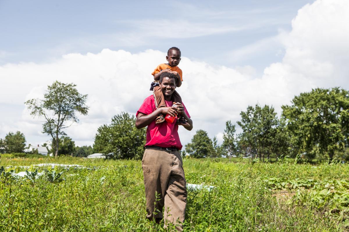 Hussein Muktar with a child on his shoulders in the field