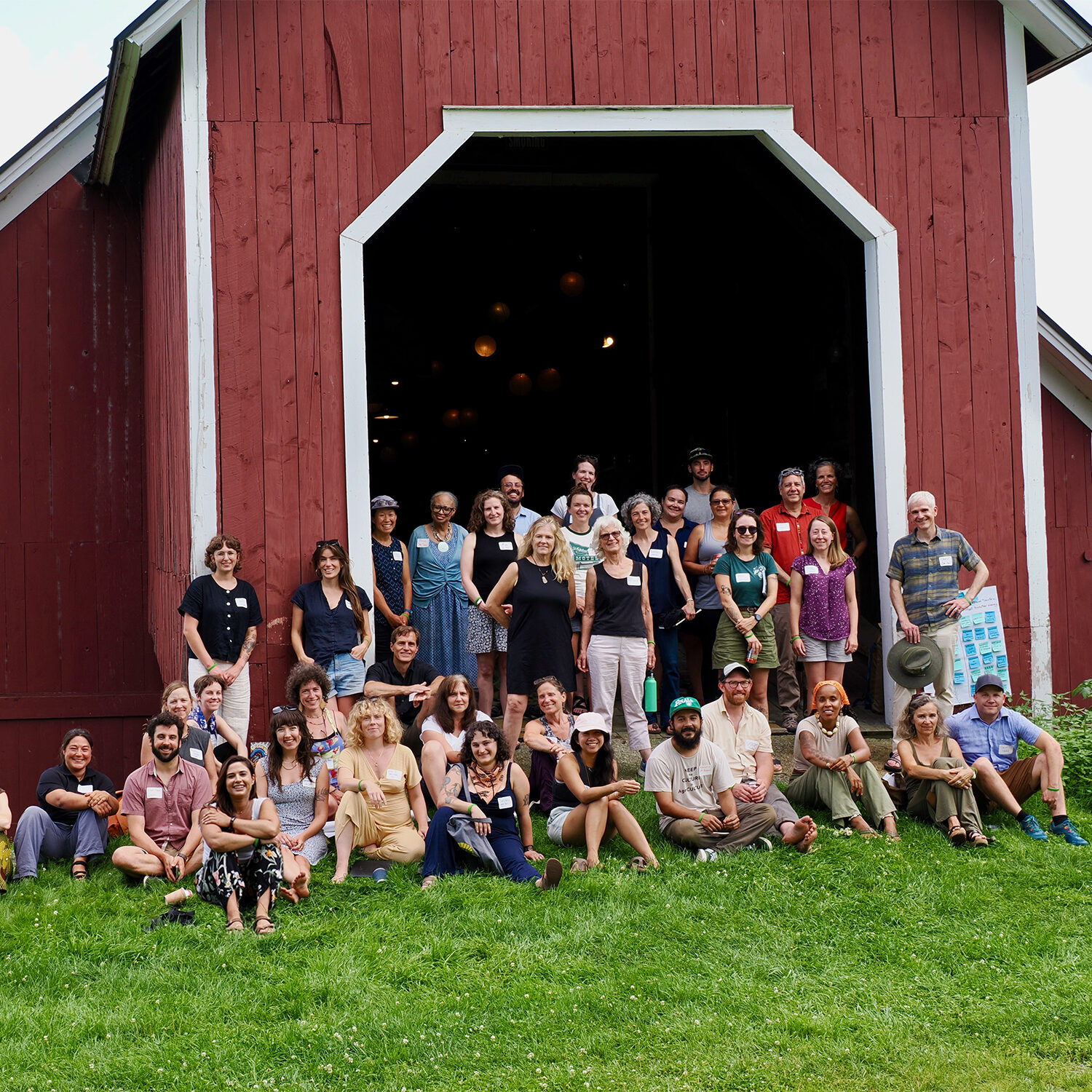 red barn with workshop participants sitting in grass before it