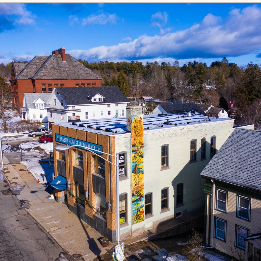 Photo of a building on a town block, brick facade with solar panels on the roof.